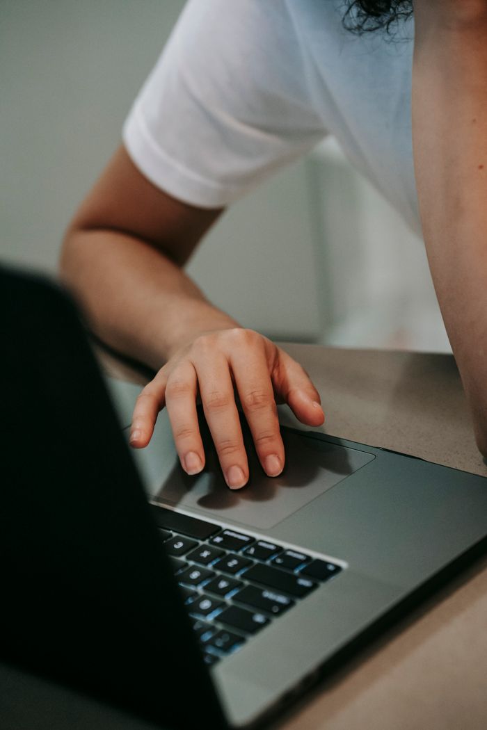 Crop anonymous female freelancer browsing laptop placed on table while doing remote job at home